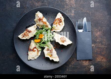 Gnocchi. Tradizionali gnocchi di carne fatti in casa serviti su un piatto nero. Suggerimento per servire il piatto. Vista dall'alto. Foto Stock