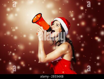 Giovane donna vestita come Santa Claus gridando in un megafono.foto con copia spazio. Foto Stock