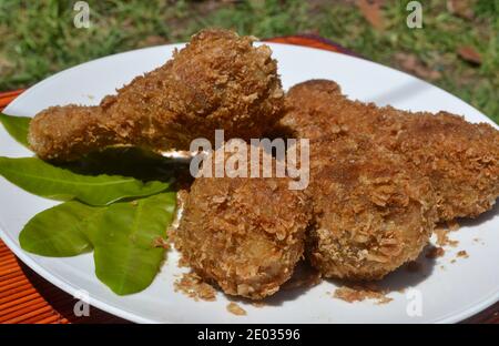 Quattro zampe di pollo fritte croccanti su piatto bianco, fast food fritti Foto Stock