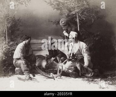 Fotografia d'annata del XIX secolo - cacciatori che pattinano un cervo nella neve, composizione in studio di William Notman, Canada, circa 1880s. Foto Stock