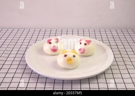 Colazione carina per i bambini, Dim Sum fantasia, tre panelli cinesi al vapore in piatto bianco. Forma della faccia di maiale Foto Stock