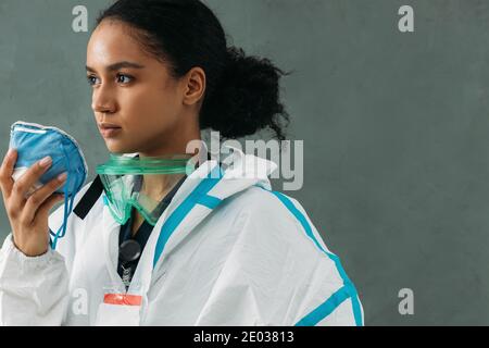 Giovane medico che tiene un respiratore che indossa un vestito protettivo Foto Stock
