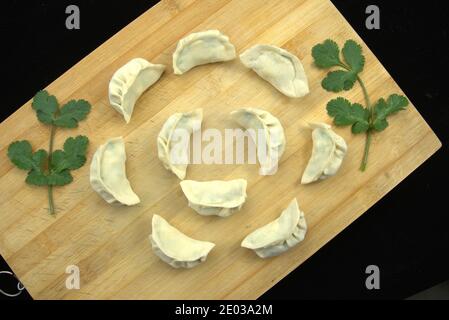 Gnocchi grezzi sul tagliere disposti a forma di fiore, sfondo nero, piatti tradizionali cinesi fatti in casa, vista dall'alto, piatto Foto Stock