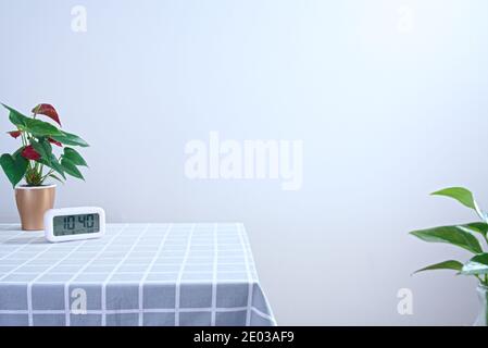 Poinsettia in vaso e sveglia digitale su tovaglia a scacchi nella parete del soggiorno, spazio di copia, minimalismo Foto Stock