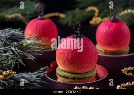 Tre dolci mousse sotto forma di palle di Natale su sfondo scuro. Festa di Capodanno. Foto Stock