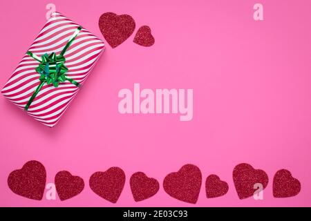 Cornice rosa con cuori. Concetto di giorno e amore di San Valentino. Scheda romantica con disegno d'arte e spazio di copia per il testo. Modello carino con una confezione regalo a righe Foto Stock