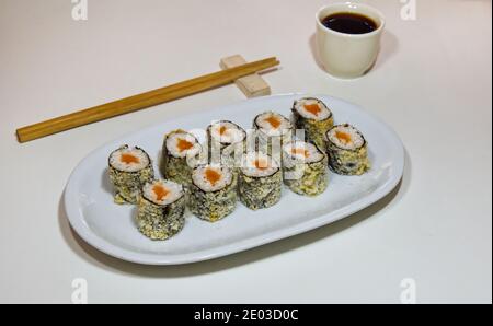 Panini giapponesi di sushi su piatto bianco lungo di porcellana su tavolo bianco, vista dall'alto, cibo sano Foto Stock