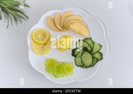Piatto di frutta e verdura a fette su sfondo bianco, vista dall'alto Foto Stock