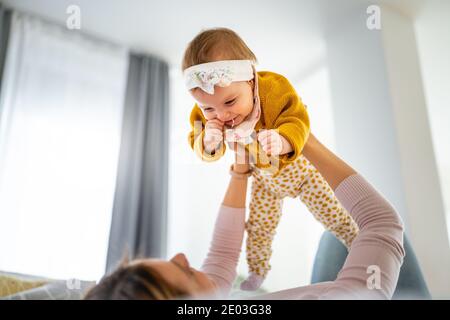 Madre e bambina giocano, abbracciano, baciano a casa. Buona famiglia. Foto Stock