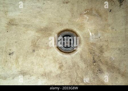 Un foro di scarico in un vecchio lavandino sporco e danneggiato. Contaminazione del foro di scarico in un vecchio bagno non svuotato Foto Stock