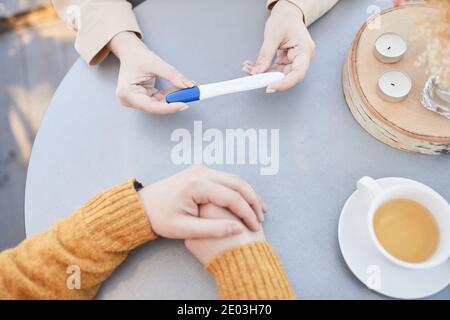 Vista ad angolo alto della donna che mostra il test di gravidanza a lei marito durante la colazione al tavolo Foto Stock