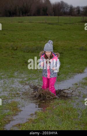 Giovane ragazza che gioca in puddddle fangose. Inghilterra Foto Stock