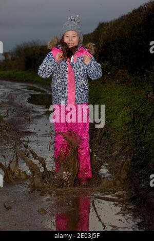 Giovane ragazza che gioca in puddddle fangose. Inghilterra Foto Stock