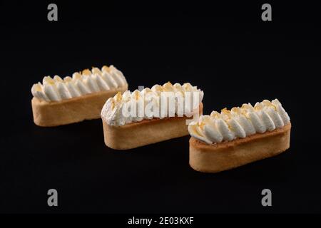 Tre dolci appena fatti in casa, isolati su sfondo nero. Biscotti shortbread con mascarpone panna montata. Concetto di dolci, industria alimentare. Foto Stock