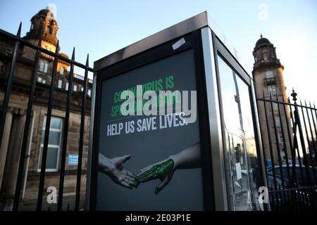 Un poster relativo a Coronavirus su una scatola telefonica fuori Glasgow Royal Infirmary dopo gravi restrizioni di blocco sono stati annunciati per dicembre e gennaio con tutto il paese che si sposta nel più alto livello di blocco dal giorno di Santo Stefano. Foto Stock