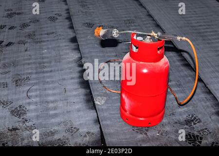 Bruciatore a gas sulla costruzione di una casa di famiglia. Isolamento del pavimento in asfalto. Cantiere. Bruciatore propano butano. Foto Stock