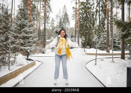 Ritratto di donna africana felice che pattina sulla pista di pattinaggio in il parco nella giornata invernale Foto Stock