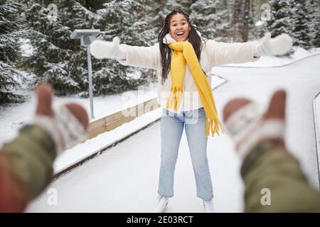 Felice donna che pattina sulla pista di pattinaggio con il suo ragazzo che catturarla Foto Stock