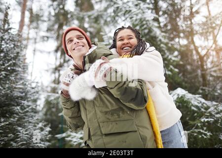 Felice giovane coppia che si diverte insieme durante la loro passeggiata in foresta invernale Foto Stock