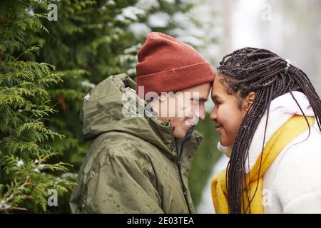 Coppia giovane amorevole che si guarda l'un l'altro faccia a faccia in piedi nella foresta invernale all'aperto Foto Stock