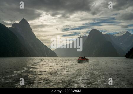 Barca turistica e montagne a Milford Sound, Nuova Zelanda Foto Stock