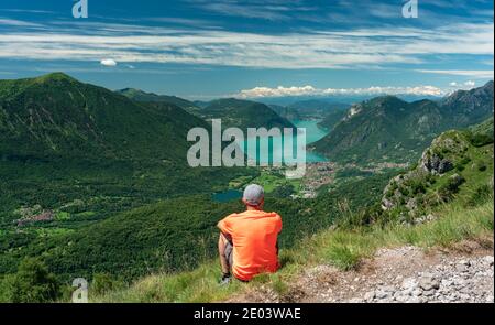 Seduto da dietro guardando il Lago di Lugano dal cima della montagna Foto Stock