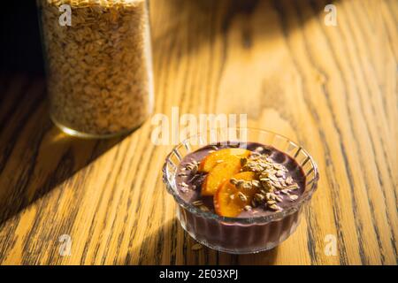 Frullato Acai, muesli, semi, frutta fresca in una ciotola di vetro su un tavolo di legno. Mangiare una ciotola sana per la colazione. Vista dall'alto. Foto di alta qualità Foto Stock