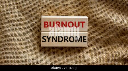 Simbolo della sindrome di Burnout. Blocchi di legno formano le parole 'sindrome di Burnout' su uno sfondo di tela bella. Sindrome di business, psicologica e burnout Foto Stock