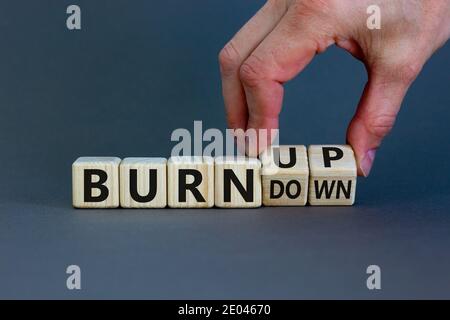 Bruciare, non bruciare. La mano maschile capovolge un cubo di legno e cambia le parole 'bruciare' in 'bruciare'. Splendido sfondo grigio, spazio per la copia. Affari, psy Foto Stock