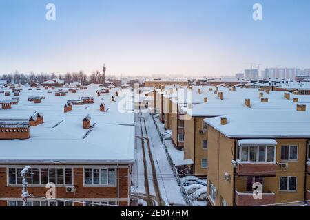 Tetti innevati di case in inverno. Panorama della città, vista dall'alto. Foto Stock