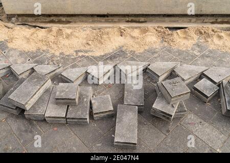 Preparazione per la posa di lastre di pavimentazione sul substrato di ghiaia. Piastrelle di pavimentazione colorate ordinate allineate in pile Foto Stock