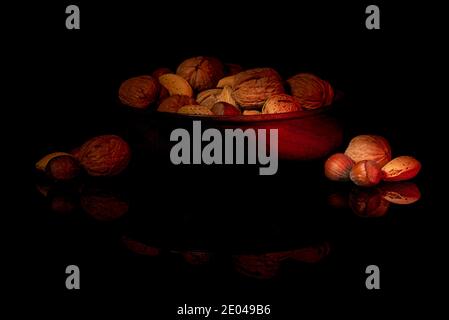 Noci biologiche, mandorle, nocciole, noci pecan in ciotola di legno con illuminazione laterale Foto Stock