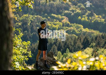 Trail Runner sorge su una roccia in montagna Foto Stock