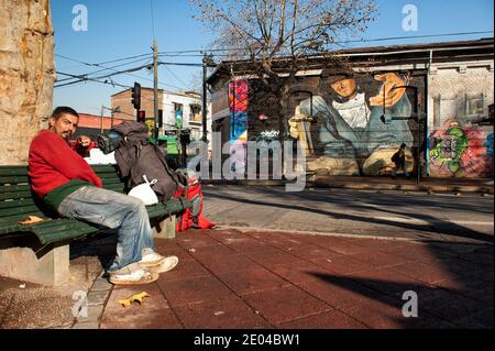 Senzatetto nella strada di Santiago del Cile, con graffiti di Street art dietro. Foto Stock