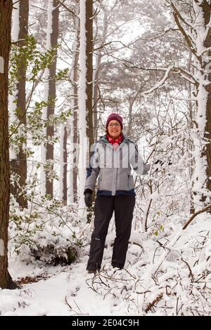 Donna che cammina lungo un sentiero in bosco innevato Inverno su Bosley Cloud vicino a Congleton Cheshire Inghilterra UK Foto Stock