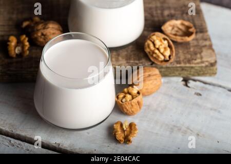 Noci biologiche e bicchiere di latte di noce su fondo di legno. Foto Stock