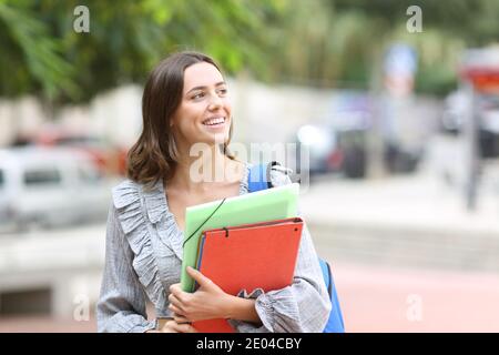 Felice studente che cammina verso la macchina fotografica guardando il lato in via Foto Stock