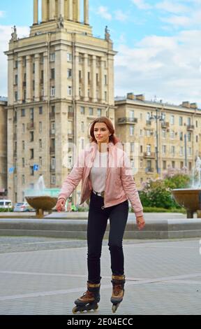 Ragazza che corre su pattini a rotelle sullo sfondo dell'alto edificio Stalin a San Pietroburgo Foto Stock