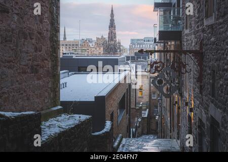 Una vista da Advocate's Close verso Princes Street a Edimburgo e il monumento Scott una mattina di dicembre dopo una notte di nevicate. Foto Stock