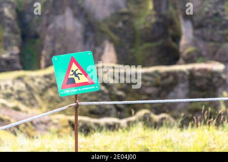 Cartello di avvertimento gli escursionisti agaist un bordo pericoloso scogliera lungo il percorso in un parco in una soleggiata giornata estiva Foto Stock