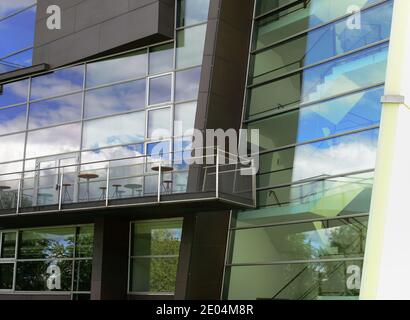 facciata di un edificio moderno con un riflesso della cielo nelle finestre e con un balcone Foto Stock