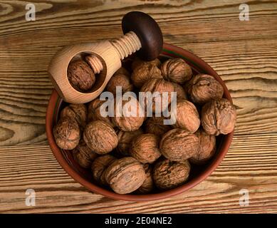 noci in una ciotola e un nutcracker di legno su un sfondo di legno Foto Stock