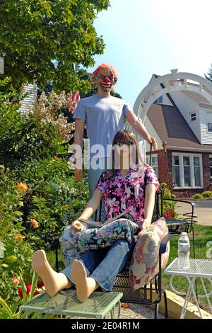 Kelly il manichino legge un libro mentre Kevin il manichino si avvicina da dietro in una maschera di Halloween nel cortile anteriore di una casa dell'Ohio. Foto Stock