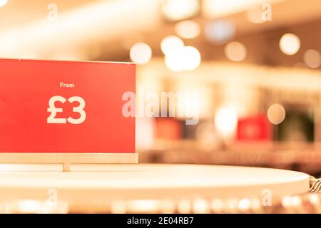 Oxford, UK -14 Dic 2020: Vendita rossa closeup tag prezzo in Hennes e Mauritz AB negozio, prezzi da tre libbre segno, sfondo sfocato dietro il segno Foto Stock