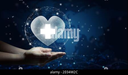 Mano che tiene un cuore bianco con il simbolo della croce bianca. Sfondo della mappa del mondo. Assistenza sanitaria, assicurazione sanitaria, beneficenza, e medicina concetto. Spazio di copia. Foto Stock