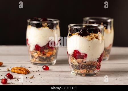 Vista laterale di deliziosi bicchieri di parfait di frutta e yogurt ripieni di strati di muesli, semi di chia, frutti di bosco freschi, avena arrotolata e yogurt fatto in casa serviti Foto Stock