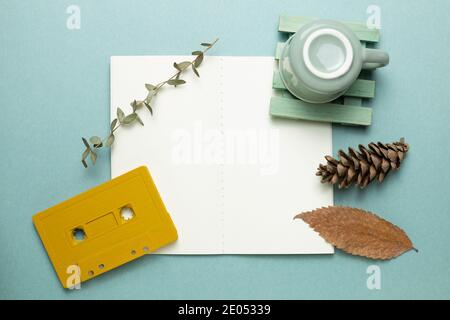 Apri un notebook vuoto con tazza, cassetta audio, pianta asciutta su sfondo verde. Concept autunno e inverno. Vista dall'alto, spazio per la copia Foto Stock