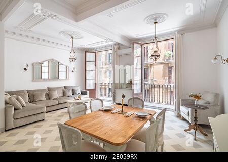 Camera classica con tavolo da pranzo, servita per due persone, pavimento in piastrelle, pareti luminose, balconi ed elementi d'arredo d'epoca Foto Stock