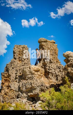 Mono Lago fossile roccia arrampicata giovane escursionista godendo la vista attraverso il lago di Natron da una delle formazioni rocciose. Sierra Nevada, California. Foto Stock