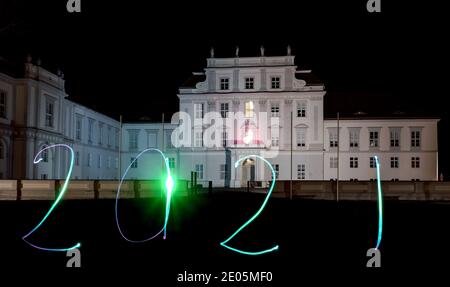 Oranienburg, Germania. 29 Dic 2020. Una donna ha disegnato l'anno 2021 con una torcia di fronte al Castello di Oranienburg (Brandeburgo). (Esposizione a lungo termine) credito: Paul Zinken/dpa/Alamy Live News Foto Stock